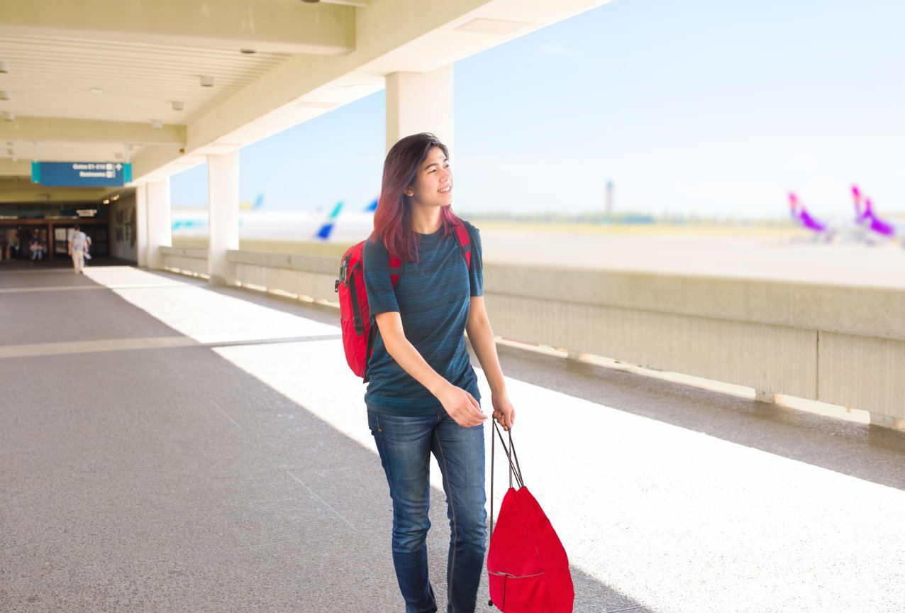 Teen girl walking through outdoor airport terminal